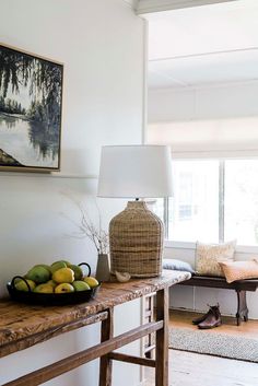 a table with some fruit on it and a lamp in the corner next to it