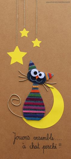 a card with a cat sitting on top of the moon and stars hanging from strings