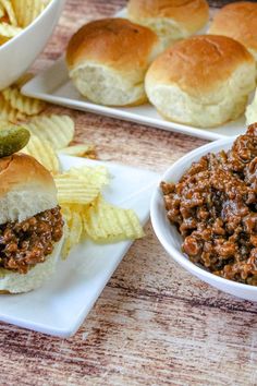 two plates filled with sloppy joe sandwiches and chips