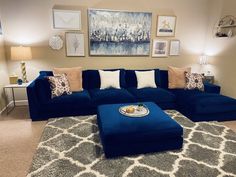 a living room with blue couches and pictures on the wall above it, along with an ottoman