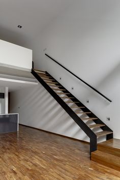 an empty room with wooden floors and stairs