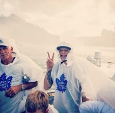 two men on a boat giving the peace sign while another man stands in front of them