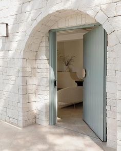 an open door leading to a living room with a couch in the corner and potted plant