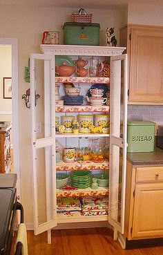 an open refrigerator in a kitchen with lots of dishes on the shelves and plates inside