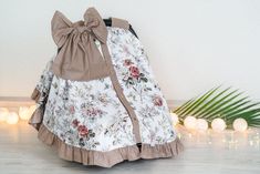 a white and brown flowered dress sitting on top of a wooden floor