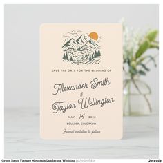 save the date card with mountains and trees on it in front of a vase filled with flowers