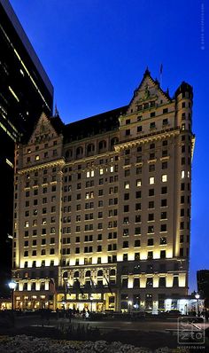 the hotel is lit up at night in front of tall buildings