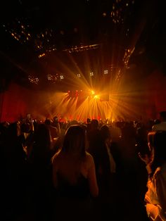 a group of people standing in front of a stage with bright lights on the floor