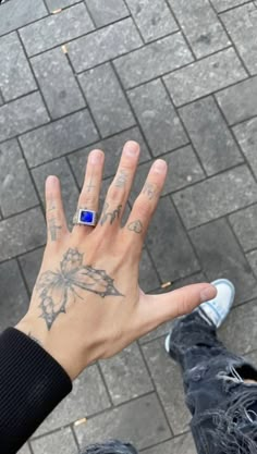 a person's hand with tattoos on it and a blue ring in the middle