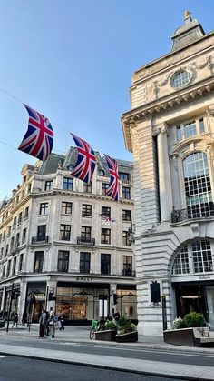 the british flag is flying in front of an old building with people walking by it