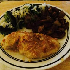 a white plate topped with meat and veggies on top of a wooden table