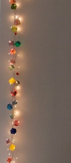 a string of lights hanging from the side of a white wall with multiple colored lamps attached to it