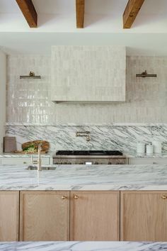 a kitchen with white marble counter tops and wooden cabinetry, along with exposed beams