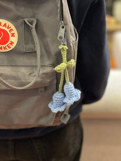 a person wearing a backpack with a crocheted cross hanging from it's side