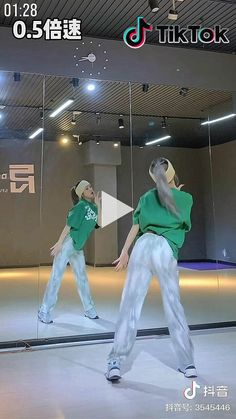 two people in green shirts and white pants are dancing on a stage with mirrors behind them