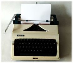 an old fashioned typewriter sitting on top of a white table next to a pair of scissors