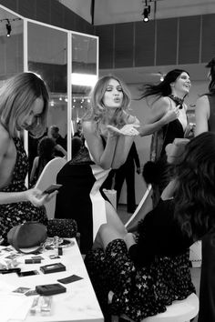 three women sitting at a table looking at cell phones and other items on the table