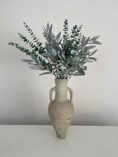 a vase with some plants in it on a table