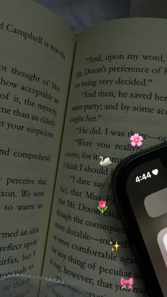 an open book with pink flowers on it and a cell phone in the foreground