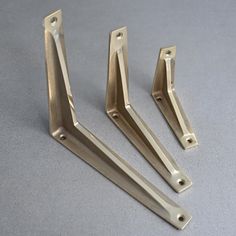 three metal brackets on a gray surface