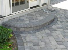 a brick patio with steps leading up to the front door and side windows on both sides