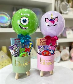 two balloons with faces on them are sitting in a cup filled with candy and candies