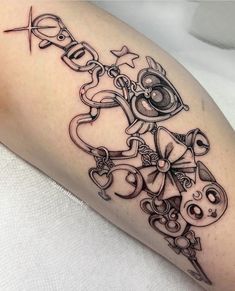 a black and white photo of a tattoo design on the leg with scissors, keys and hearts