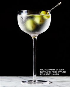 an image of a martini with limes in the glass on the table and black background