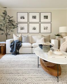 a living room filled with white furniture and pictures on the wall above it's coffee table