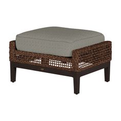 the ottoman is made from wicker and has a gray cushion on top of it