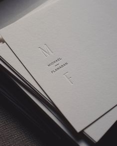 three folded business cards sitting on top of each other with the letter m in them