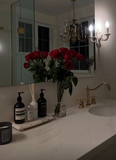 a bathroom sink with soap, lotion and flowers in it next to a mirror