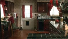 a woman sitting at a kitchen counter in front of a stove top oven and microwave