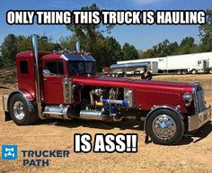 a red semi truck parked on top of a dirt field next to a white trailer