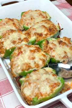 several stuffed peppers in a white casserole dish on a red and white checkered tablecloth