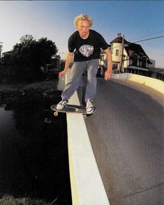 a man riding a skateboard down the side of a road next to a river