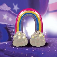 a rainbow shaped object sitting on top of a purple bed covered in stars and confetti