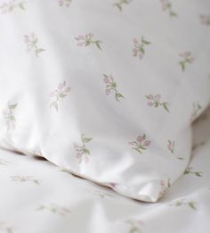 an unmade bed with white sheets and pink flowers