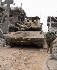 an army tank is parked in front of a destroyed building