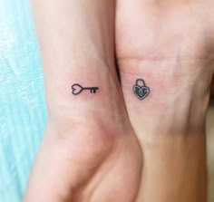 two people with matching tattoos on their arms holding each other's hands and one has a key in the shape of a heart