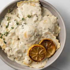 a bowl filled with mashed potatoes covered in gravy and sliced lemons