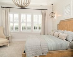 a bed sitting in a bedroom next to a window with shutters on both sides