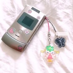 an old cell phone is laying on the bed with its keychain attached to it