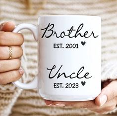 a woman holding a white coffee mug with the words brother and uncle est 202 on it