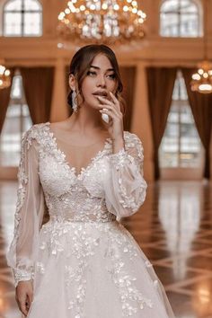 a woman in a wedding dress posing for the camera with her hand on her face