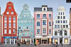 several different colored buildings on the street with people walking and riding bikes in front of them