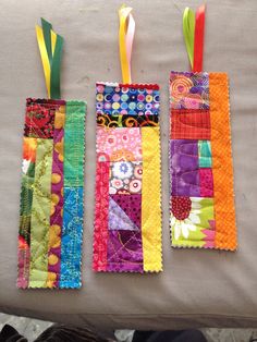 three pieces of colorful fabric hanging from the back of a couch with ribbons attached to them