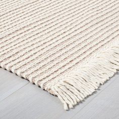 a white rug with fringes on the floor