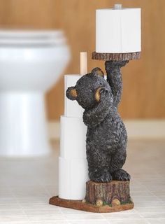 a black bear figurine holding a lit candle on top of a white pillar