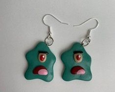 a pair of green earrings with red eyes and nose on white background, hanging from silver earwires